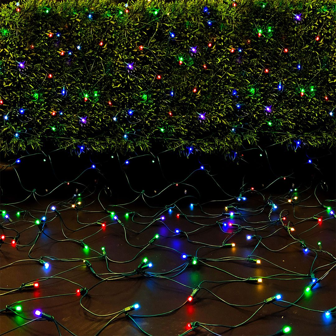 Net lights displayed lit cascading from a bush to the ground
